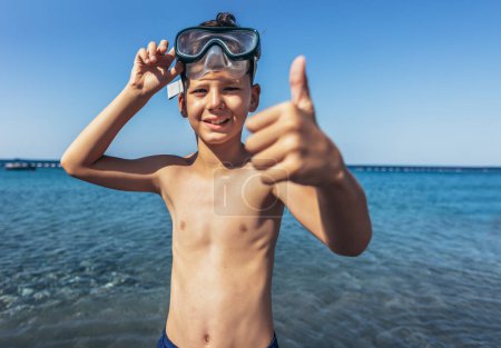 Foto de Portrait of a smiling little boy with scuba mask by the sea - Imagen libre de derechos