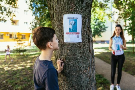 Téléchargez les photos : Les enfants sont à la recherche d'un chien disparu, portant des affiches. - en image libre de droit