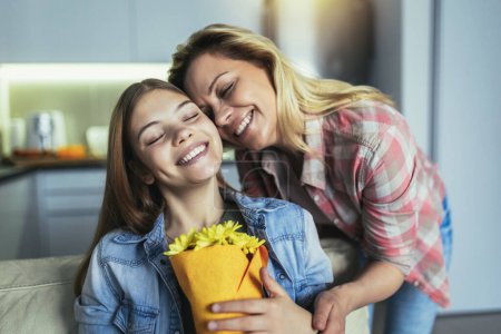 Foto de Mamá y niña sonriendo y abrazando sosteniendo flores. - Imagen libre de derechos