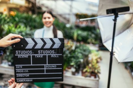 Photo for Hands holding movie clapper. Photo of interview or broadcast, woman owner in her flower shop. - Royalty Free Image