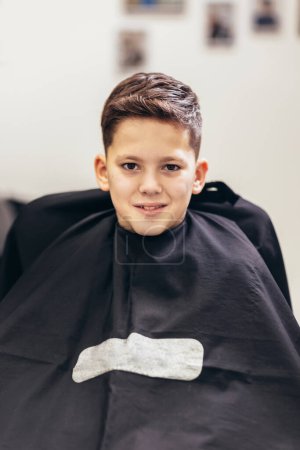 Photo for Shot of little kid covered with black cloth by hairdresser - Royalty Free Image
