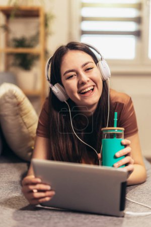 Photo for Young teen girl using digital tablet computer listening music at home - Royalty Free Image