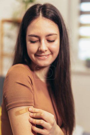 Téléchargez les photos : Cheerful teenage girl having plaster on arm .Virus protection. Covid-19 vaccination. HPV vaccine - en image libre de droit