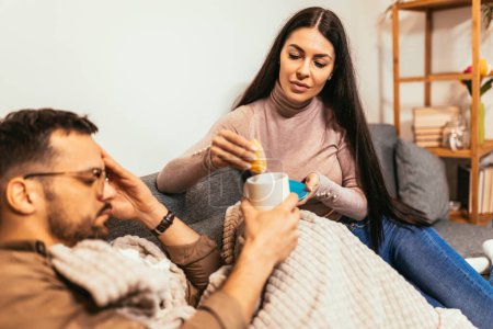 Téléchargez les photos : Jeune couple malade buvant du thé chaud à la maison concept santé, grippe et personnes - en image libre de droit