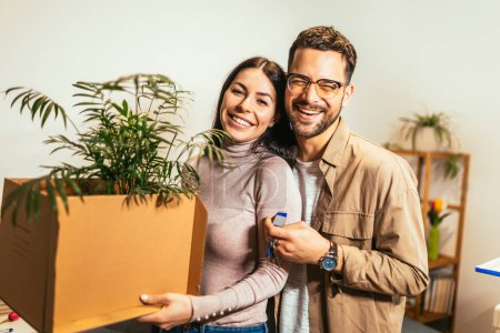 Téléchargez les photos : Couple souriant déballer des boîtes dans une nouvelle maison.Nouvelle vie.Ils montrent la clé de leur nouvelle maison. - en image libre de droit
