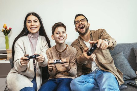 Téléchargez les photos : Famille heureuse jouant à des jeux vidéo à la maison et s'amusant ensemble. - en image libre de droit