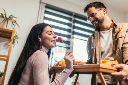 Téléchargez les photos : Man holding breakfast tray to a happy relaxed woman - en image libre de droit