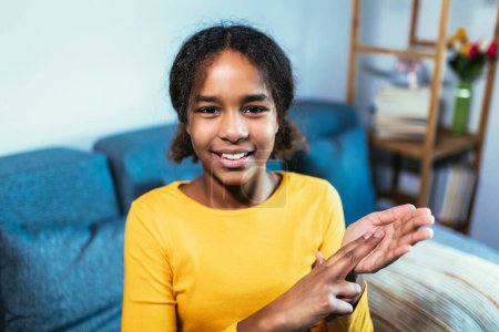 Téléchargez les photos : Belle fille sourde noire souriante utilisant le langage des signes à la maison - en image libre de droit