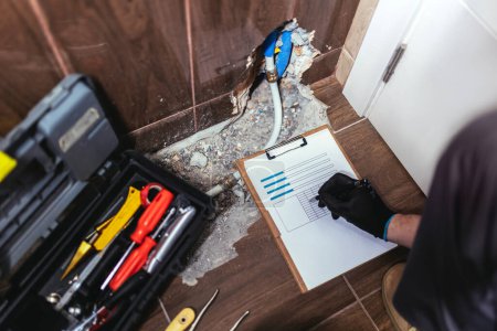 Photo for Handyman describes the extent of the of a damaged wall in the bathroom for insurance and verification purposes - Royalty Free Image