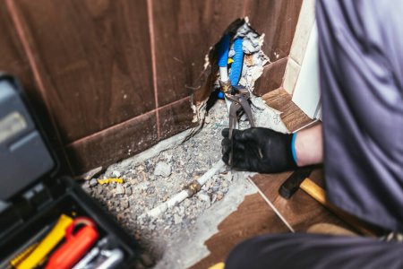 Téléchargez les photos : Tuile murale cassée et pendant la réparation du rail chauffé. Un bricoleur répare un tuyau dans la salle de bain. - en image libre de droit