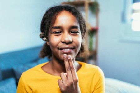 Téléchargez les photos : Beautiful smiling black deaf girl using sign language at home - en image libre de droit