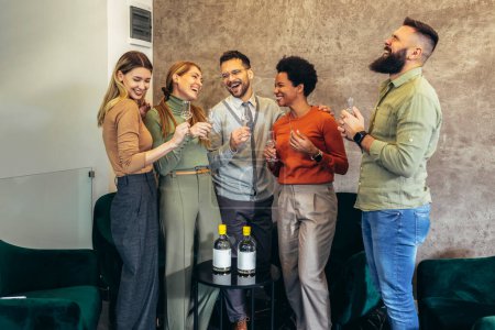 Téléchargez les photos : Group of  businesspeople sitting together in a co-working space and celebrating with alcohol drink. - en image libre de droit