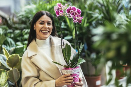 Téléchargez les photos : Jeune femme achetant des fleurs dans un centre de jardin - en image libre de droit