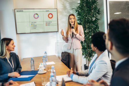 Foto de Business people having a meeting or presentation and seminar in the office. Portrait of a young business woman leade. Business people sitting in a room listening to the motivator coach. - Imagen libre de derechos