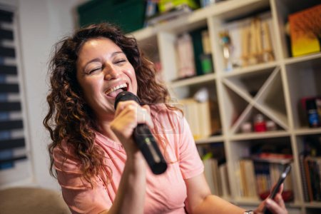 Foto de Mujer feliz cantando karaoke en casa. - Imagen libre de derechos