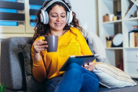 Foto de Mujer con auriculares relajándose en casa con música, disfrutando del tiempo libre. - Imagen libre de derechos