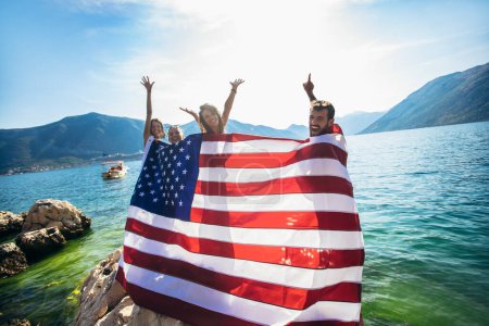 Foto de Grupo de amigos felices con bandera americana en el día de la independencia de la playa, vacaciones de verano y el concepto de personas - Imagen libre de derechos