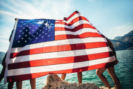 Foto de Grupo de amigos felices con bandera americana en el día de la independencia de la playa, vacaciones de verano y el concepto de personas - Imagen libre de derechos