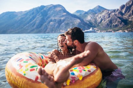 Téléchargez les photos : Jeune couple avec anneaux gonflables s'amusant à la mer en vacances d'été. - en image libre de droit