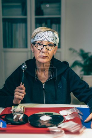 Foto de Mujer mayor traficante de drogas con básculas para pesar drogas. Las drogas conceptuales son heroína o cocaína. Embalaje en polvo blanco - Imagen libre de derechos