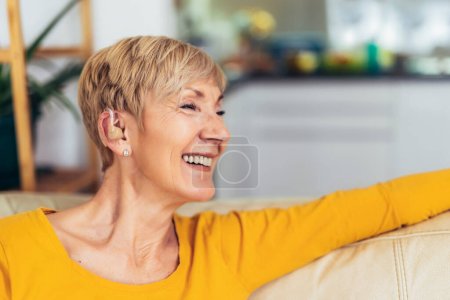 Reife Frau mit Hörgerät drinnen lächelnd