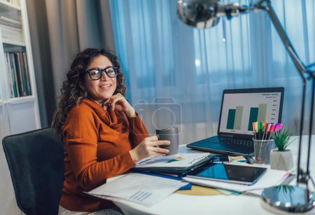 Photo for Young beautiful woman working on a laptop in her home office - Royalty Free Image