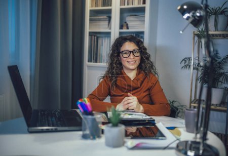 Téléchargez les photos : Jeune belle femme travaillant sur un ordinateur portable dans son bureau à la maison - en image libre de droit