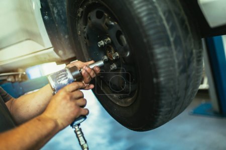 Foto de Mecánico cambiando la rueda del coche en el taller de reparación de automóviles, de cerca. - Imagen libre de derechos