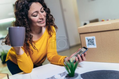 Photo for Woman affixing QR codes onto storage boxes. She is focused on her task, carefully placing the QR codes onto each box with precision. Concept organization, efficiency, or technology in storage management. - Royalty Free Image