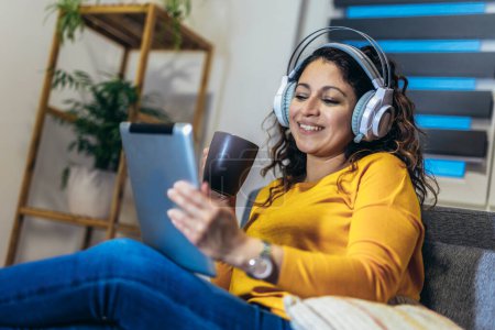 Foto de Mujer con auriculares relajándose en casa con música, disfrutando del tiempo libre. - Imagen libre de derechos