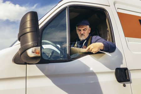 Téléchargez les photos : Chauffeur de camion vérifiant la liste d'expédition assis dans le véhicule utilitaire blanc - en image libre de droit