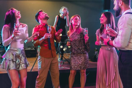 Foto de Grupo de personas bailando en el club con DJ en segundo plano - Imagen libre de derechos
