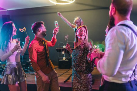 Photo for Group of people dancing in the club with DJ in background - Royalty Free Image