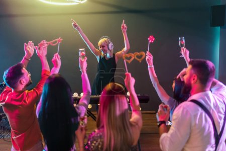 Téléchargez les photos : Groupe de personnes dansant dans le club avec DJ en arrière-plan - en image libre de droit