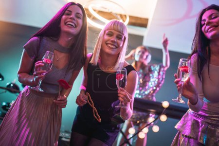Foto de Grupo de personas bailando en el club con DJ en segundo plano - Imagen libre de derechos