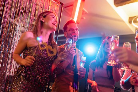 Téléchargez les photos : Groupe d'amis faisant la fête dans une boîte de nuit et trinquant à des boissons
. - en image libre de droit