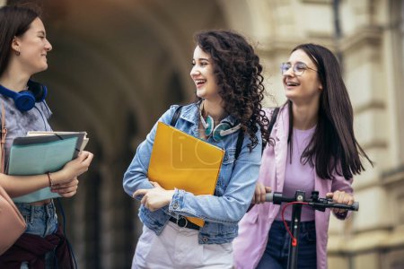 Téléchargez les photos : Étudiante en scooter rencontre avec ses camarades de classe sur le campus - en image libre de droit