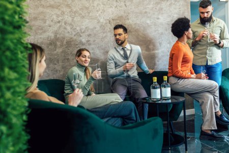Photo for Group of  businesspeople sitting together in a co-working space and celebrating with alcohol drink. - Royalty Free Image