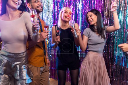 Photo for Group of people dancing in the club singing karaoke. - Royalty Free Image