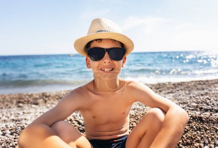 Foto de Portrait of a smiling boy on the beach with a straw hat. - Imagen libre de derechos