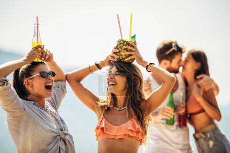 Foto de Jóvenes amigos divirtiéndose en la playa en un día soleado. - Imagen libre de derechos