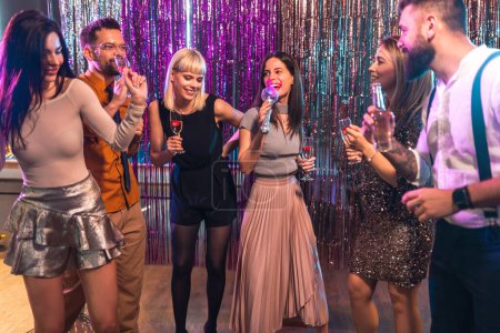 Group of people dancing in the club singing karaoke.