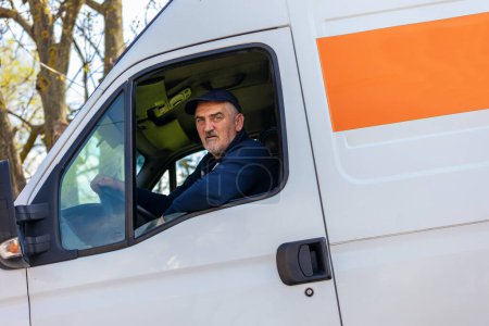 Téléchargez les photos : Portrait d'un livreur joyeux regardant par la fenêtre du véhicule utilitaire blanc, livrant des marchandises en voiture - en image libre de droit