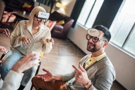 Photo for Business team having fun at corporate training, funny teambuilding activity, playing game guess who in the office. - Royalty Free Image
