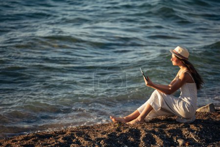 Foto de Adolescente usando una tableta digital para tomar fotos en la playa - Imagen libre de derechos