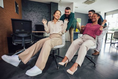 Photo for Group of professional people racing with the chairs while on a break in the modern office - Royalty Free Image