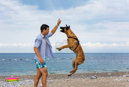 Ein Hundetrainer mit einem Hund beim Training in der Nähe des Meeres