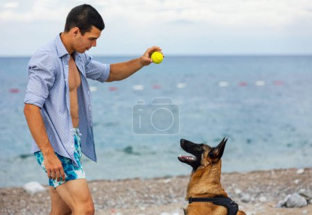 Photo for A dog trainer with a dog during training near the sea - Royalty Free Image