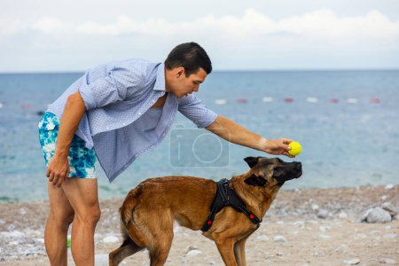 Téléchargez les photos : Un dresseur de chien avec un chien pendant l'entraînement près de la mer - en image libre de droit