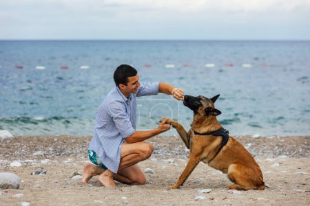 Photo for A dog trainer with a dog during training near the sea - Royalty Free Image